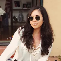 A woman wearing sunglasses sitting on a bench.