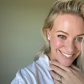 A woman with blonde hair and a white shirt is posing for a photo.