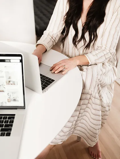A woman working on her laptop in front of a white table.