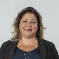 A woman wearing a black blazer and blue top.